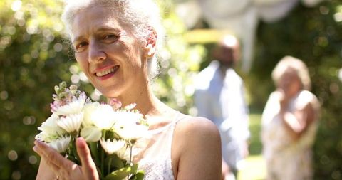 Smiling Senior Bride with Flower Bouquet at Outdoor Celebration