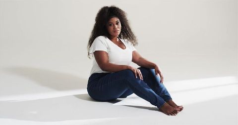 Pensive African American Woman Sitting in Minimalist Studio Environment