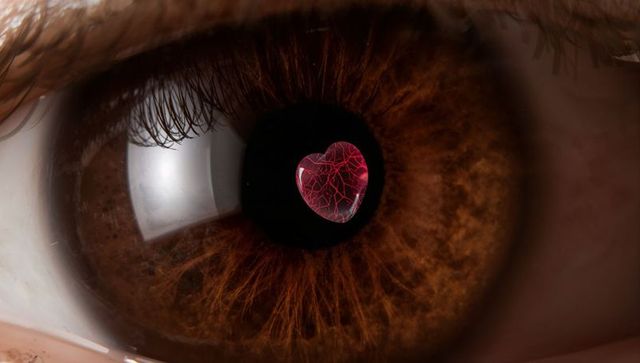 Revealing brown eye with heart-shaped red reflection in pupil, macro studio close-up