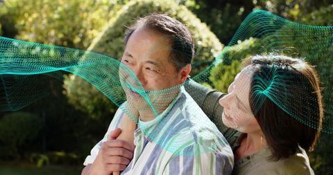 Senior couple embracing in sunlit backyard with turquoise digital wave overlay representing health