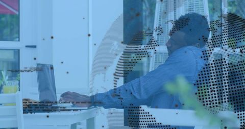 Remote worker typing on laptop in sunlit outdoor workspace with digital globe overlay
