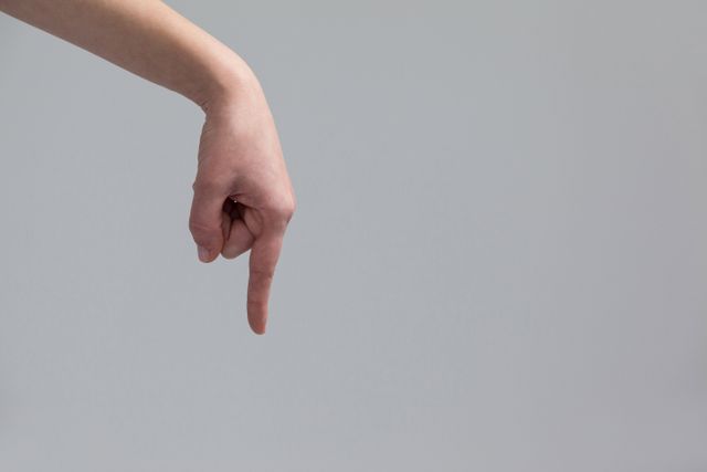 Woman's Hand Pointing Downwards on Grey Background - Download Free Stock Photos Pikwizard.com