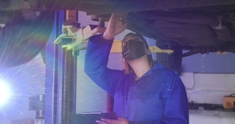 Skilled Female Mechanic in Mask Repairing Vehicle under Hoist - Download Free Stock Images Pikwizard.com