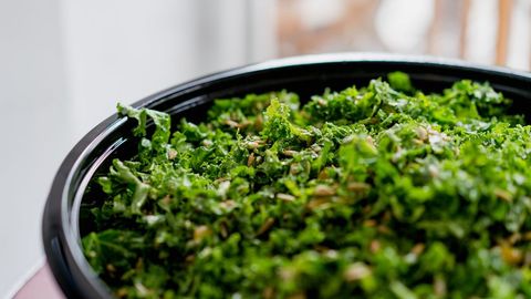 Fresh chopped kale salad with sunflower seeds in black bowl close-up healthy vegan dish