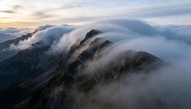 Misty Serrated Alpine Ridge with Rolling Clouds and Warm Sunrise Glow