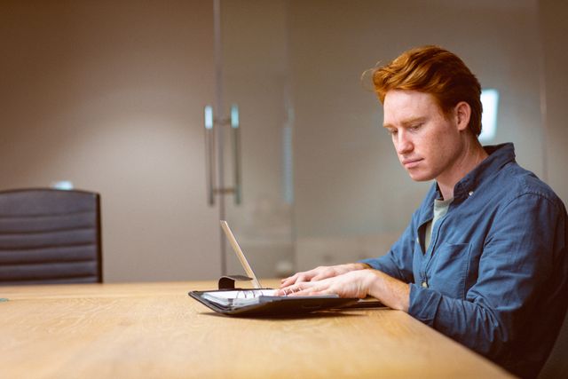 Caucasian male business professional reviewing documents at a desk in a modern office. Ideal for use in business, entrepreneurship, and professional settings. Perfect for illustrating concepts of work, focus, and productivity in a contemporary workspace.