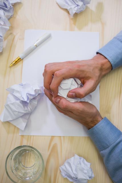 Hands of business executive making paper ball on a desk
