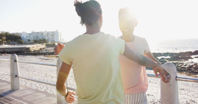 Young friends hugging at beach during a sunny day, showing happiness and friendship. Ideal for themes around summer vacation, coastal living, friendship, leisure activities, and happiness.