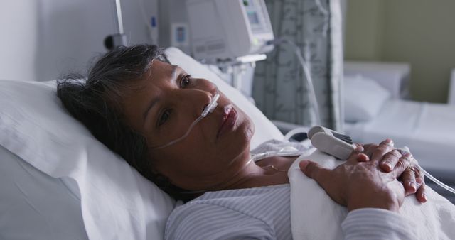 Elderly woman reclining in hospital bed wears oxygen tube and appears resting. Scene suggests hospital's serene, clean environment. Image can illustrate healthcare services, patient care, hospital treatment, medical recovery, or aging issues. Suitable for use in medical blogs, healthcare websites, or informational brochures.