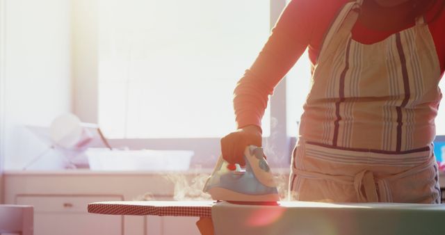 Person Ironing Clothes in Sunny Kitchen - Download Free Stock Images Pikwizard.com