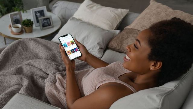 Smiling Woman Relaxing at Home Browsing on Smartphone
