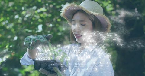 Woman checking seedlings with augmented reality data overlay in nursery for smart cultivation