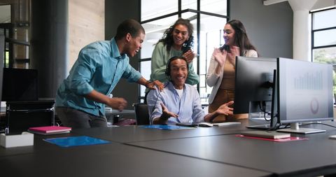 Multiracial team celebrating success in modern office environment
