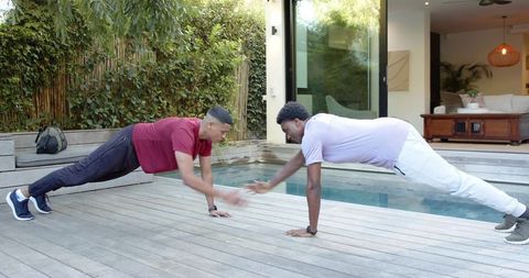 Male Friends Exercising in Plank Pose Beside Home Pool