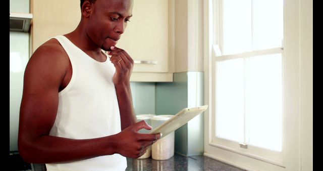 African American Man Using Digital Tablet and Eating in Kitchen - Download Free Stock Images Pikwizard.com