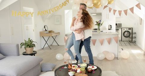 Joyfully dancing couple celebrates anniversary in decorated kitchen