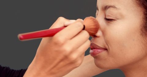 Makeup artist applying powder to woman's face
