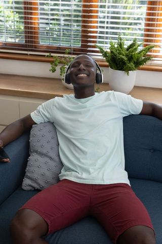 Joyful young man relaxing with wireless headphones at home