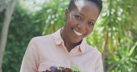 Smiling Woman Holding Fresh Garden Produce in Sunlit Background
