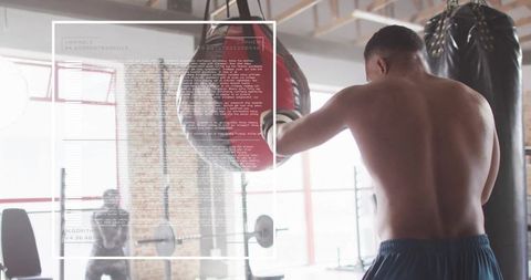 Determined boxer training at gym with punching bag