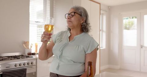 Mature Woman Enjoying Beer in Bright Modern Kitchen