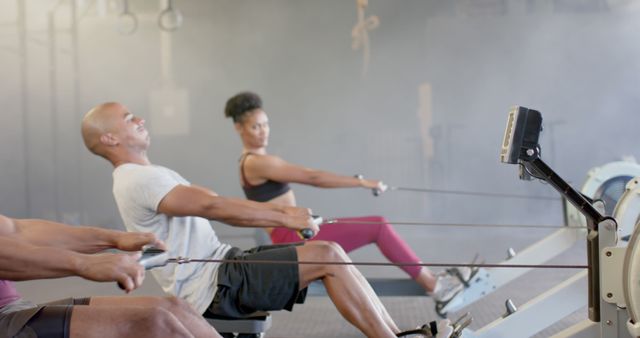 Focused people using rowing machines in an indoor gym, highlighting fitness and teamwork. Perfect for materials promoting health, exercise routines, gym memberships, training guides, or motivational resources for an active lifestyle community.