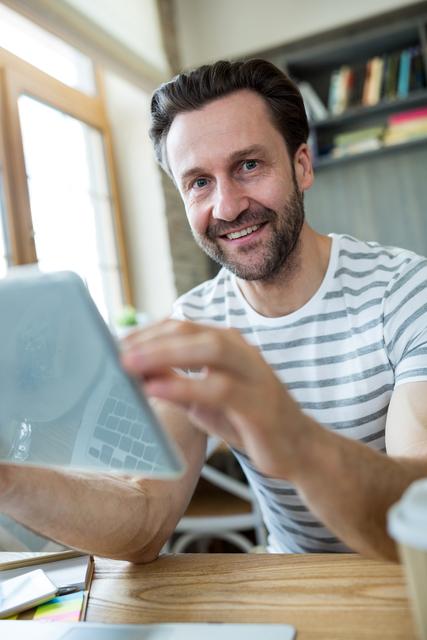 Portrait of smiling man using digital tablet in coffee shop