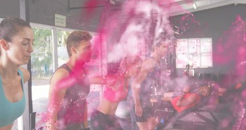 Dynamic group training with bench press and spotting amid pink powder burst, urban fitness