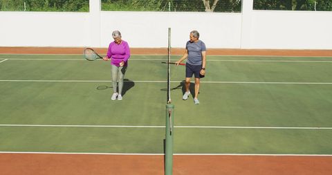 Active senior couple relaxing after tennis match on court