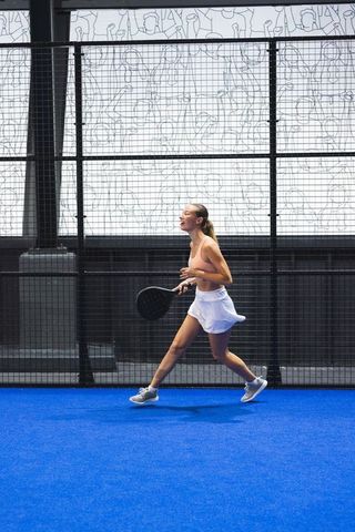 Female athlete playing padel on blue court