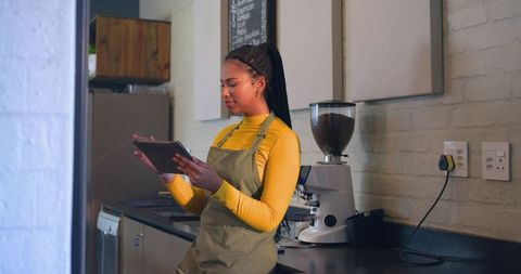 Barista checking orders on tablet at minimalist café counter with espresso grinder