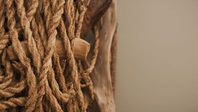 Rustic jute rope hanging on weathered wood peg, natural fiber texture and neutral tones