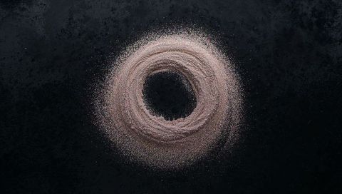 Rose gold powder ring forming textured spiral with glitter specks on dark slate surface