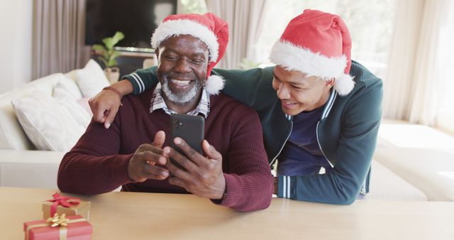 Smiling father and son celebrating Christmas with gifts and mobile phone - Download Free Stock Images Pikwizard.com