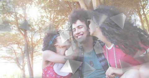 Friends kissing smiling man in sunlit park, casualwear and geometric light overlays