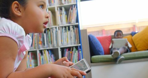 School children engaged with tablets in library environment