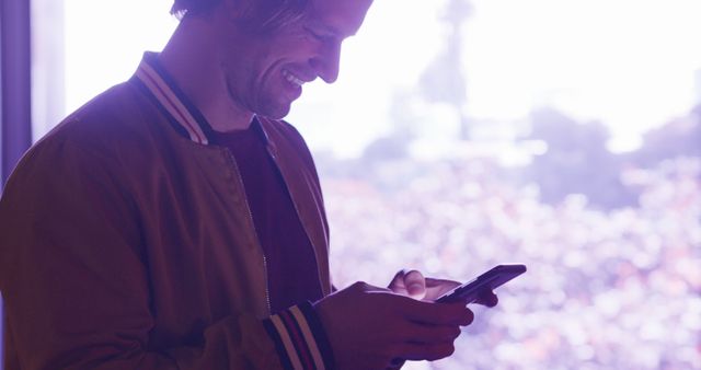 Man smiling and using smartphone with sunset background - Download Free Stock Images Pikwizard.com