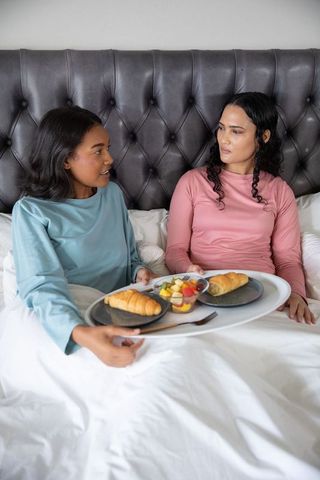 Diverse Friends Sharing Breakfast in Bed in Cozy Pajamas
