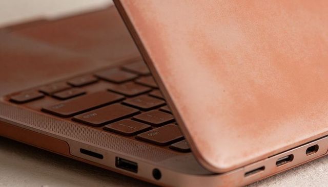 Warm leather laptop closeup showing side ports, headphone jack and textured lid detail