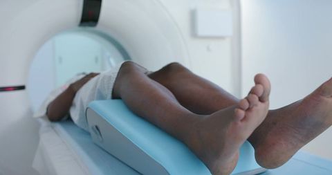 Black female patient undergoing mri on padded table wearing gown in radiology clinic