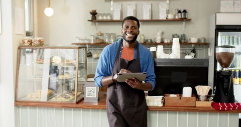 Smiling Barista with Tablet in Modern Coffee Shop