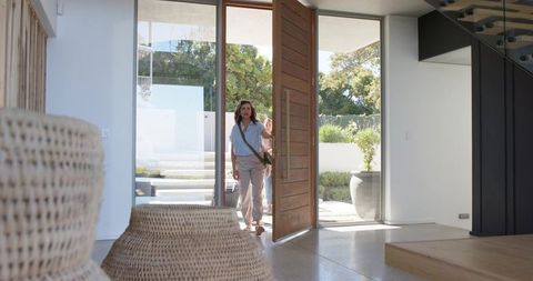 Sunlit modern entryway with woman entering carrying crossbody bag and woven baskets