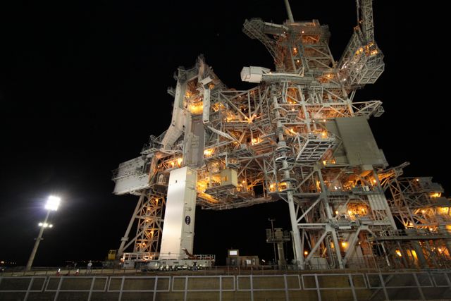 Complex night-time scene with impressive lighting showing the payload canister beneath the Rotating Service Structure's Payload Changeout Room at NASA's Kennedy Space Center, Florida. Suitable for illustrating space missions, aerospace engineering, NASA's operations, and preparations of space flights.