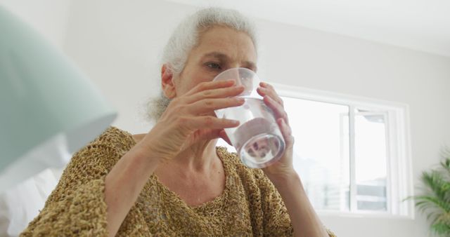 Elderly Woman Drinking Water Near Window - Download Free Stock Images Pikwizard.com