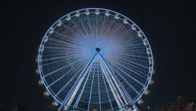 Spinning ferris wheel creating blue led light trails night carnival exposure radial pattern