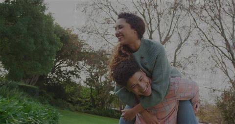 Joyful Couple Enjoying Piggyback Ride Outdoors in Autumn Garden