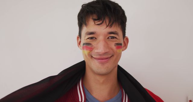 Portrait of happy biracial man with national flag and flag of germany on cheek. Spending quality time at home.