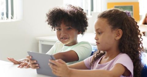 Children Collaborating on Tablet in Sunlit Classroom Sharing Digital Learning