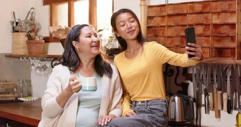 Mother and daughter taking selfie in cozy kitchen setting