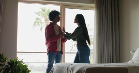 Couple enjoying scenic view through bedroom balcony door